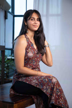 Woman wearing a patterned dress sitting indoors with a blurred background