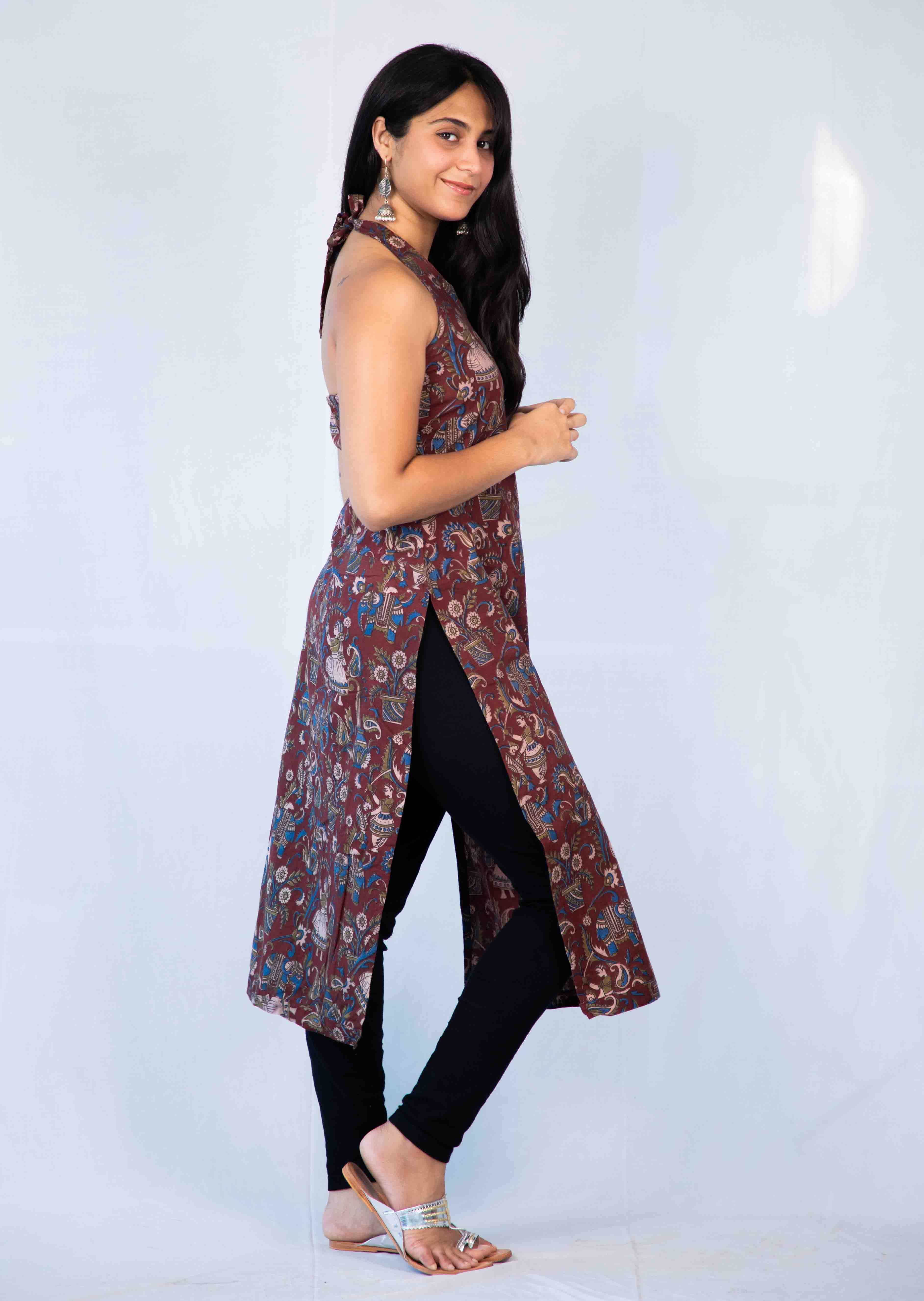 Woman wearing a patterned dress over black pants on a white background