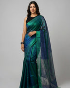 Woman wearing a green and blue saree on a gray background