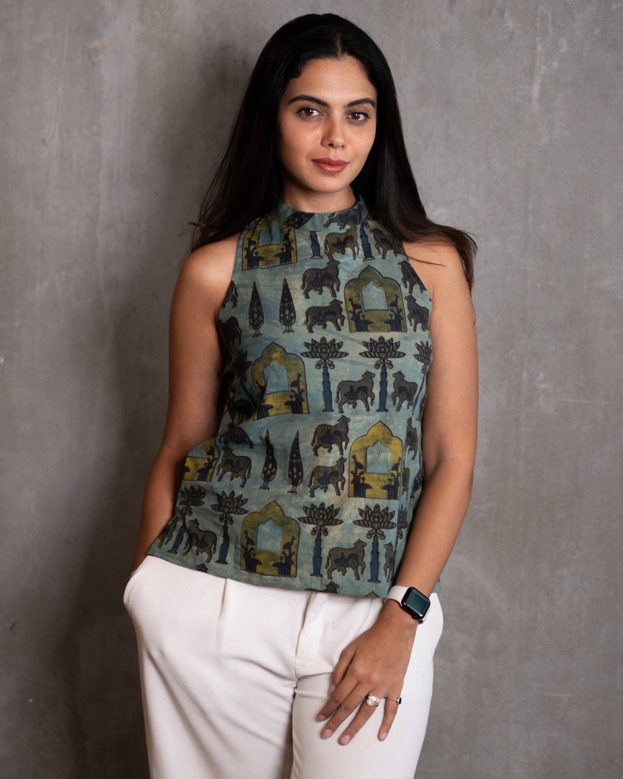 Woman wearing a sleeveless patterned top against a gray background