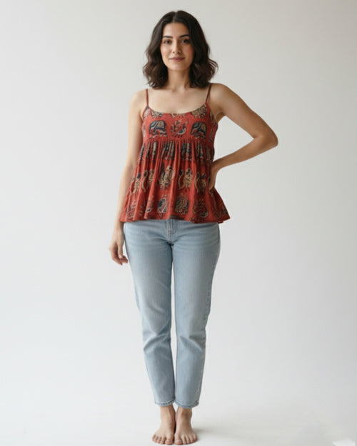 Woman wearing a patterned top and light blue jeans on a white background